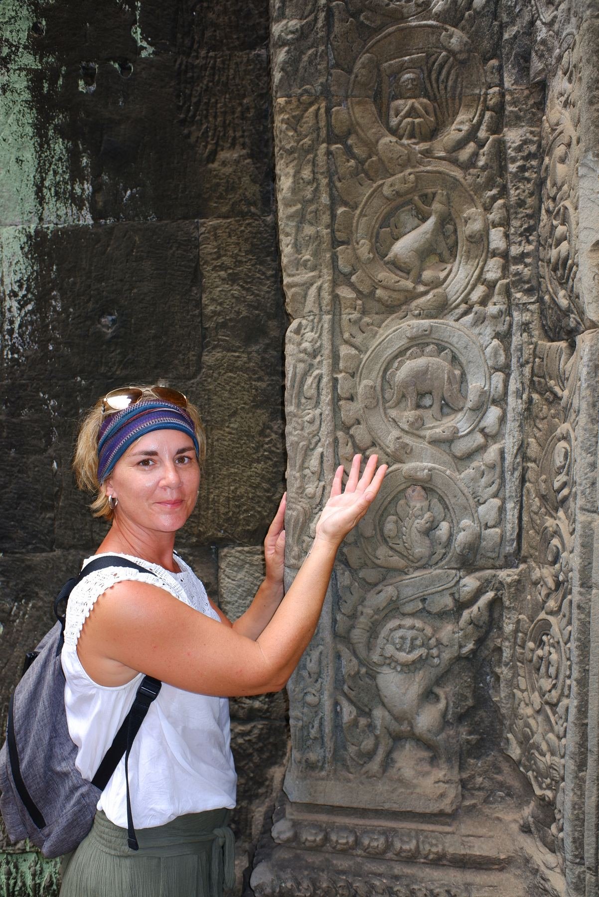 A woman traces her hand along an intricately carved stone relief depicting zodiac animals