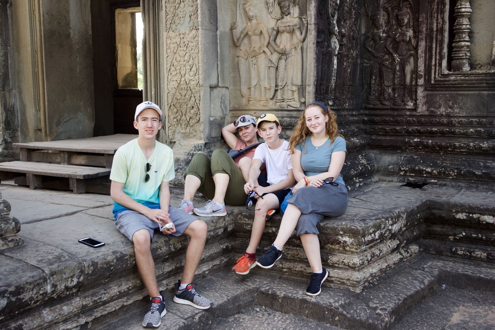 Family sitting together on the ancient stone steps of Angkor Wat